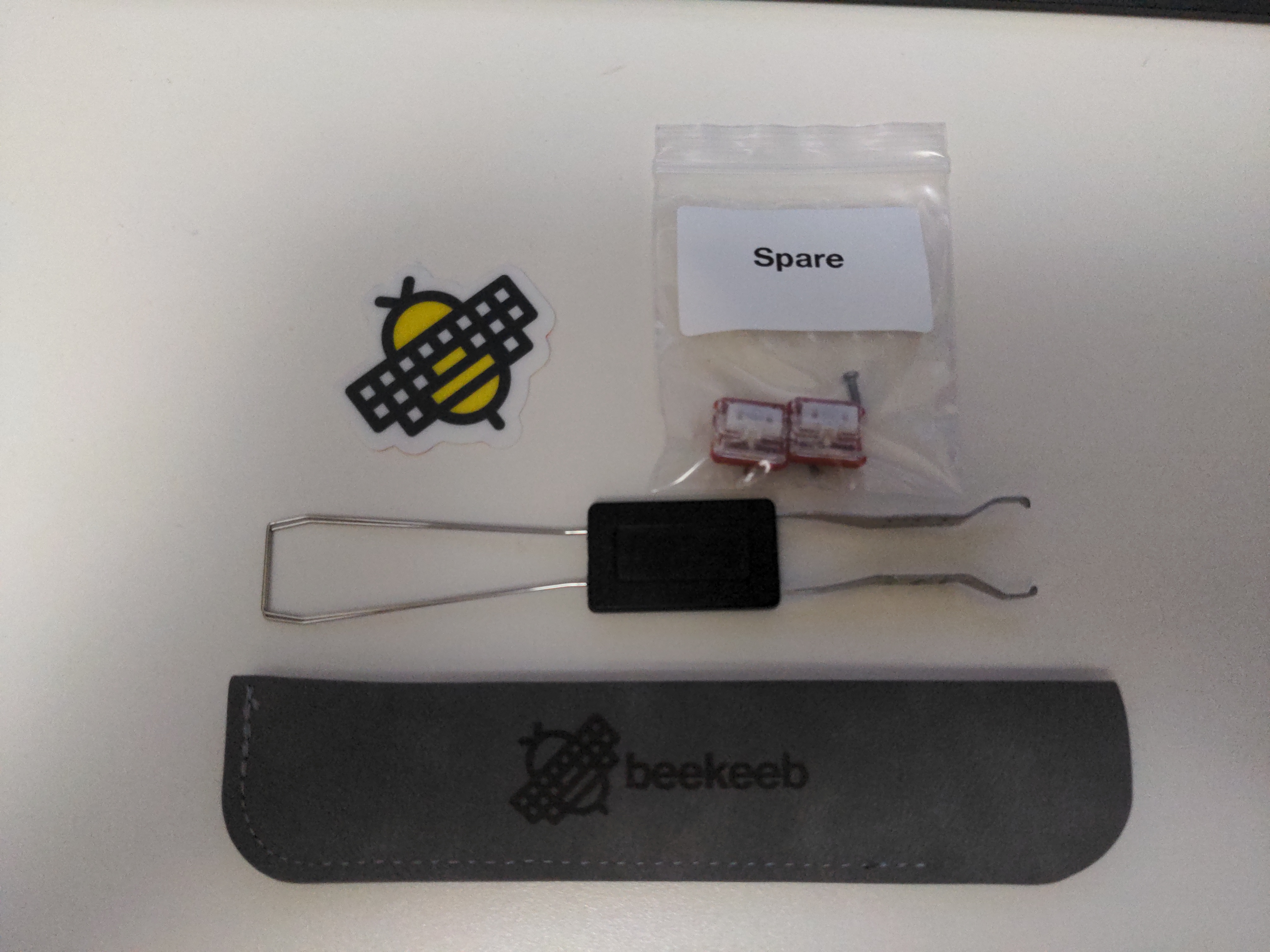 beekeeb sticker, two spare switches and a keycap/switch puller with a soft case